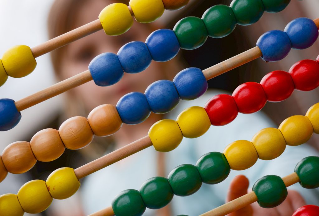 Young girl looking at a colorful wooden abacus